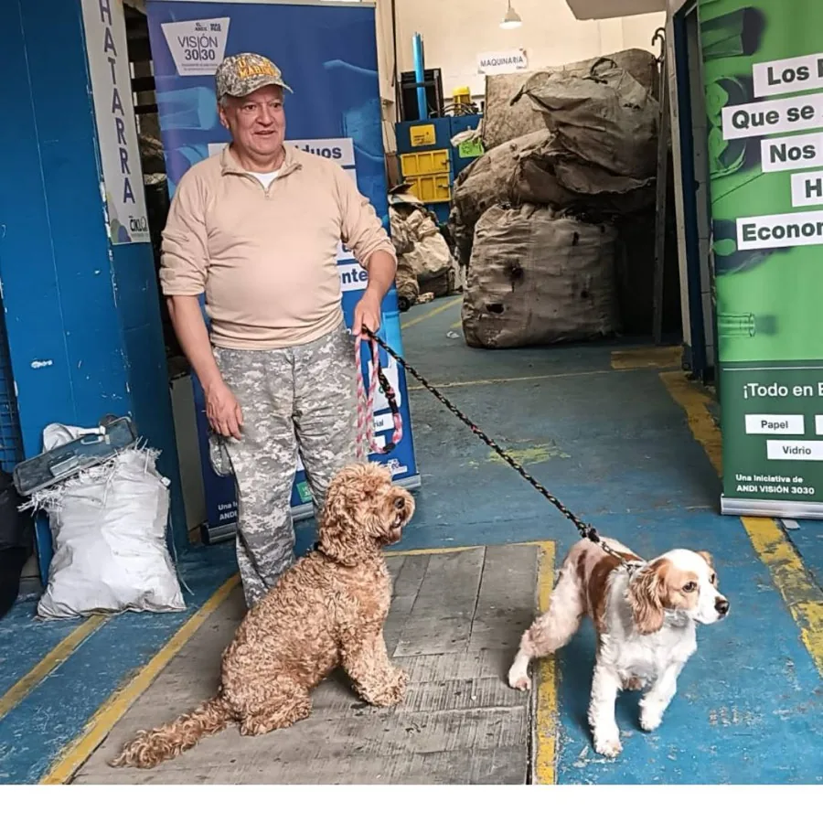 Recicladora de Familia Ciklo sonriendo con el uniforme verde de la asociación en una calle de Bogotá